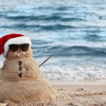 Sand Snowman with Christmas hat on beach