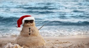 Sand Snowman with Christmas hat on beach