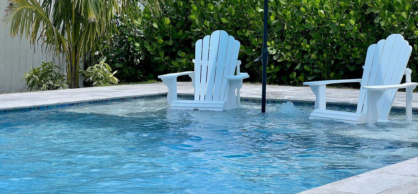 Two chairs on tanning shelf in inground pool