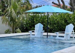 Two Adirondack chairs in pool on tanning shelf