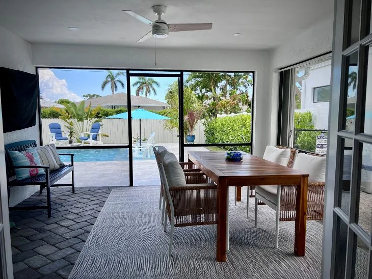 Screened lanai with flat screen TV, dining table and view to heated pool